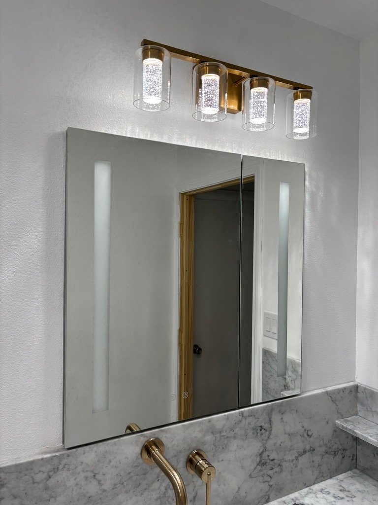 Project Gallery Backlit LED vanity mirror below a brushed brass four-light sconce