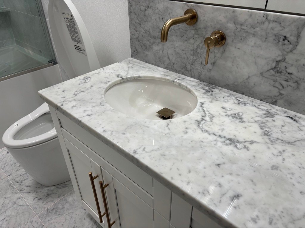 Project Gallery Carrara marble vanity top with wall-mount brushed brass faucet