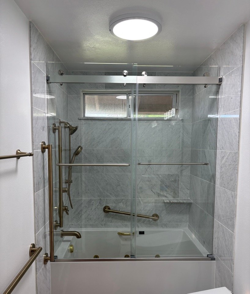 Project Gallery Frameless sliding glass shower and tub enclosure with marble tile surround